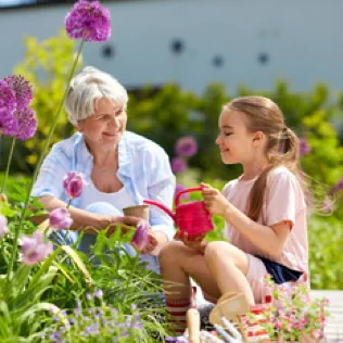 A grandmother and granddaughter smiling while gardening