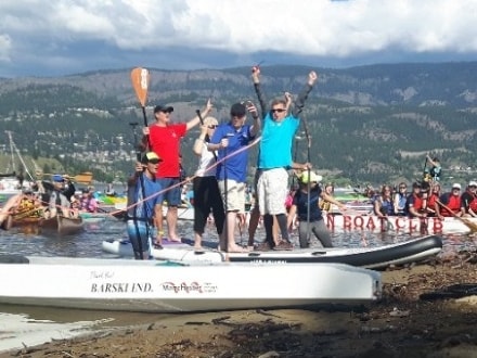 Paddle Trail participants wave their arms in the air while standing in their watercraft